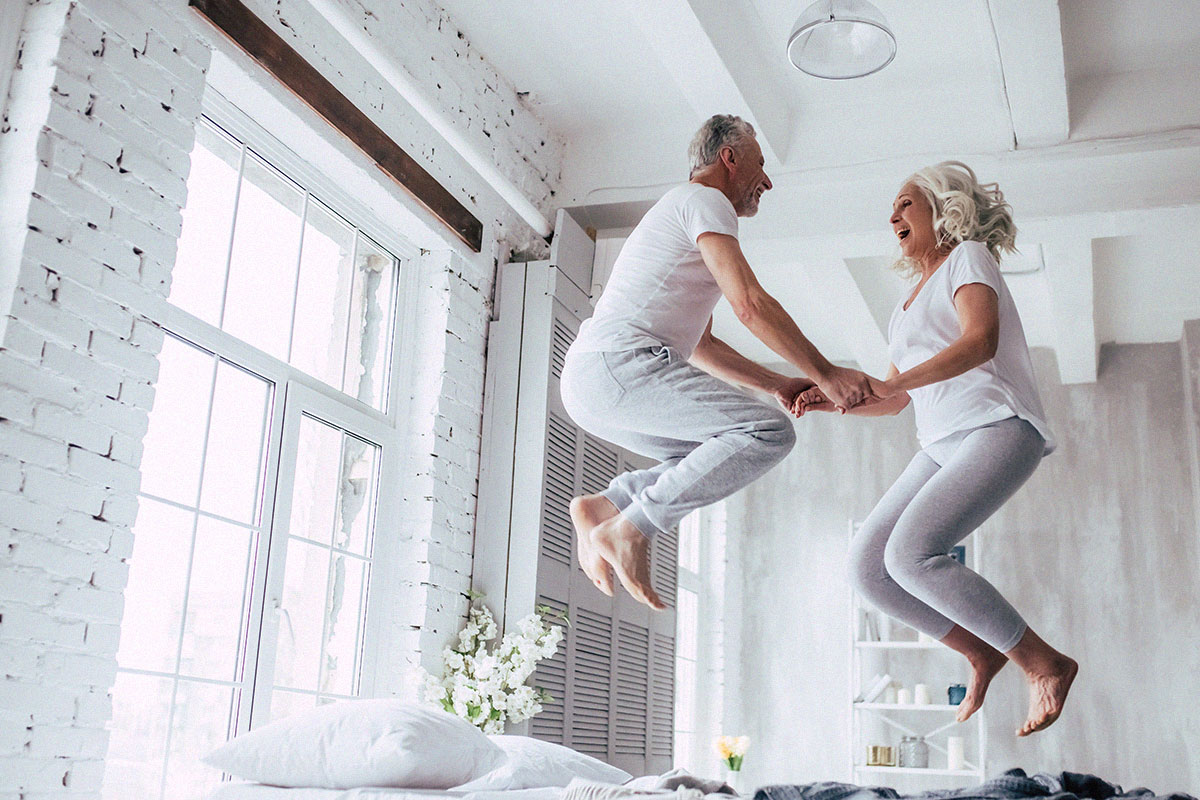 old-senior-couple-jumping-on-bed-having-fun