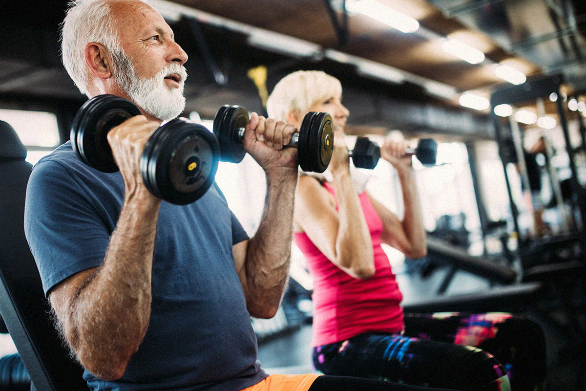 senior-couple-excercising-and-lifting-weights-at-gym
